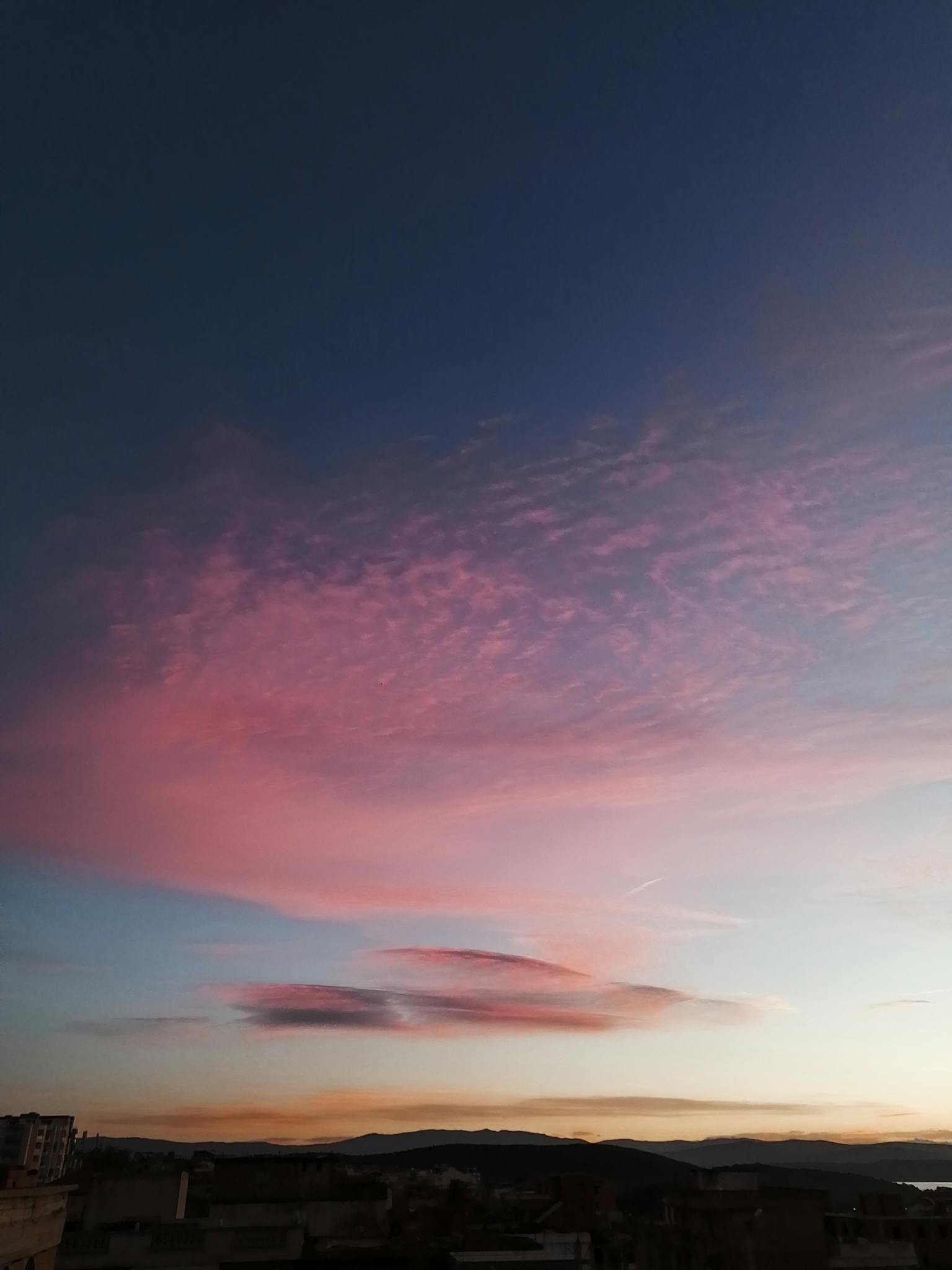 Mesmerizing pink clouds against a deep blue sky at sunset, perfect for calming wallpapers.